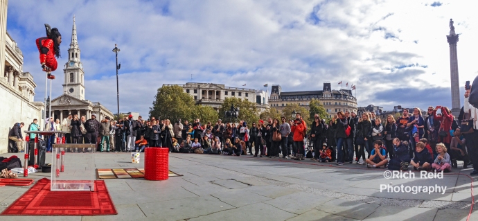 Panorama of Contortionist Yogi Laser performing for a crowd in Trafalgar Square in London, UK.